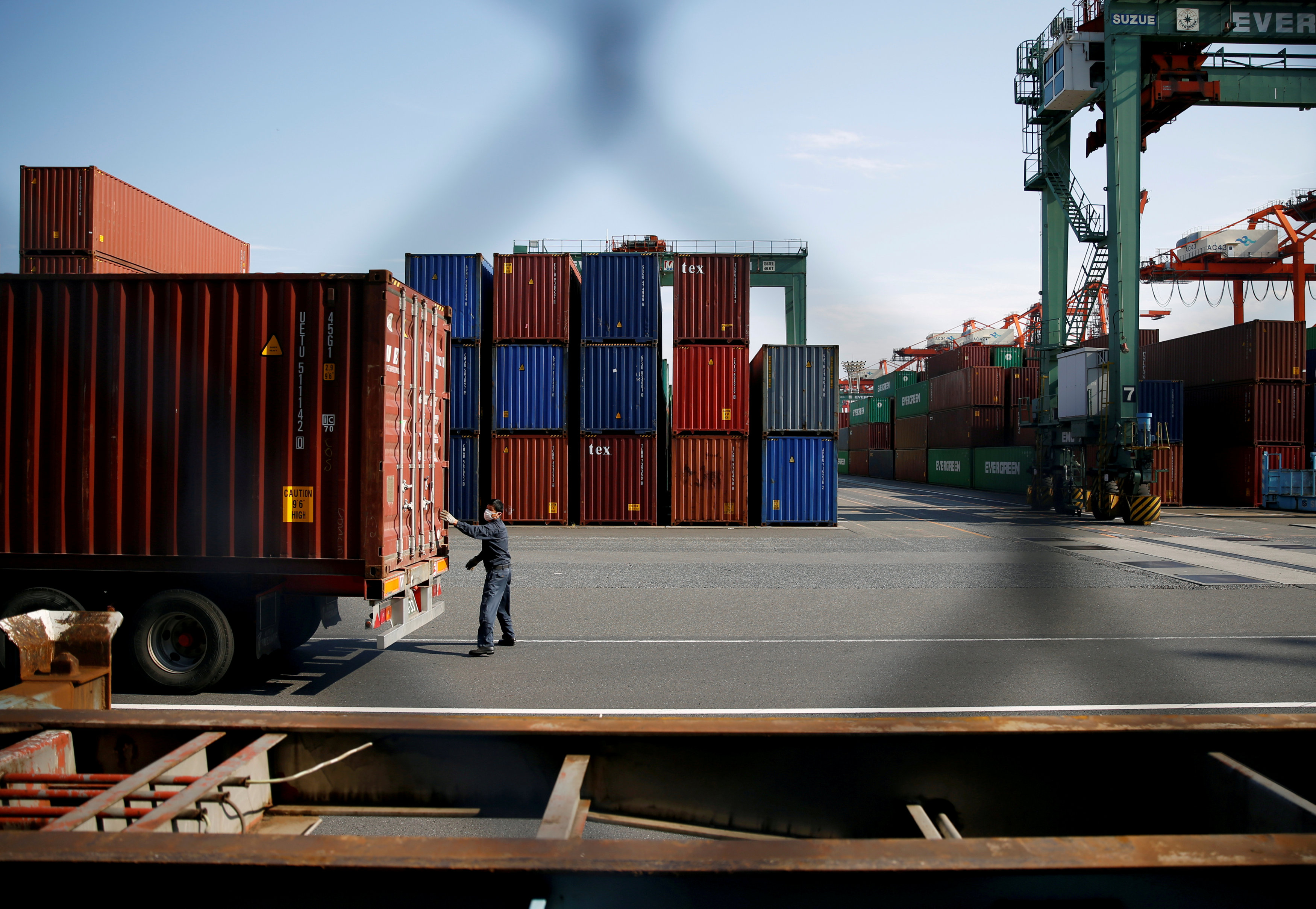 FILE PHOTO: A man works between shipping containers at a port in Tokyo, Japan