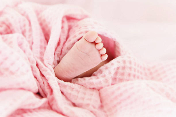 Tiny little cute baby foot under pink blanket