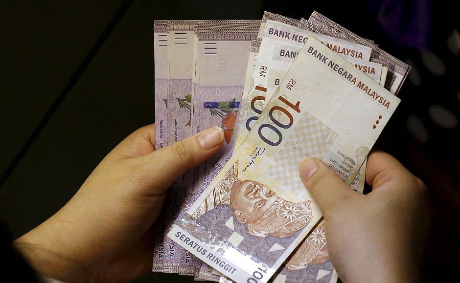 File photo of a customer counting her ringgit notes outside a money changer at the central business district in Singapore
