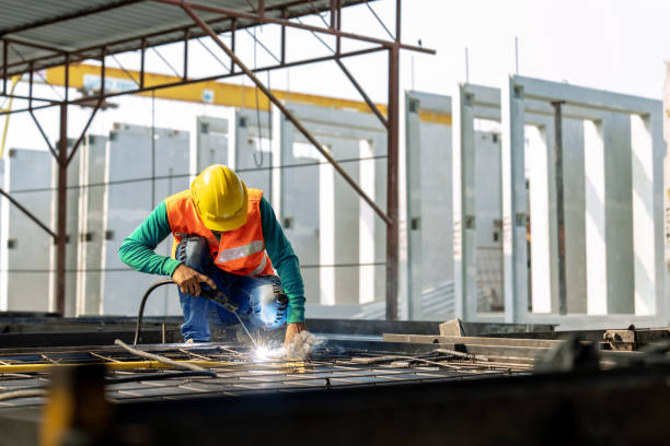 Workers at a construction site weld metal structures of precast concrete slabs